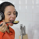 Person wearing headphones sampling spoonful of pasta